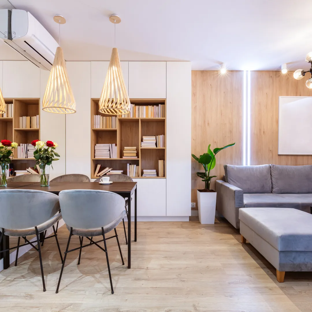 Habitación cálida que contiene un juego de comedor y un sofa. Terminaciones en madera en las paredes y pisos vinílicos.